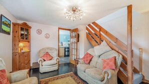 Un salon chaleureux avec un canapé, des fauteuils, un meuble en bois et un escalier.