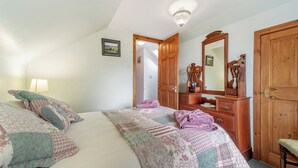 Une chambre à coucher avec un lit, une commode, un miroir et une porte.
