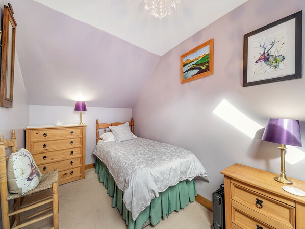 A bedroom with a bed, a dresser, a chair, and two lamps.