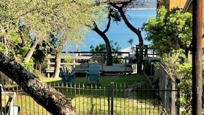 Un espace extérieur clos, avec vue sur un plan d’eau, une terrasse en bois et une chaise.