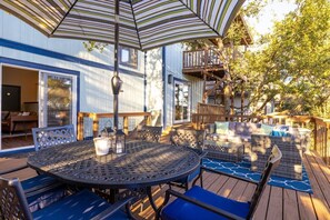 Eine Terrassenausstattung im Freien mit rundem Tisch und Stühlen, einer Holzterrasse und einem überdachten Sitzbereich.