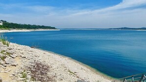 Un paysage côtier caractérisé par une rive rocheuse, une eau d’un bleu limpide et des collines qui se dessinent à l’horizon.