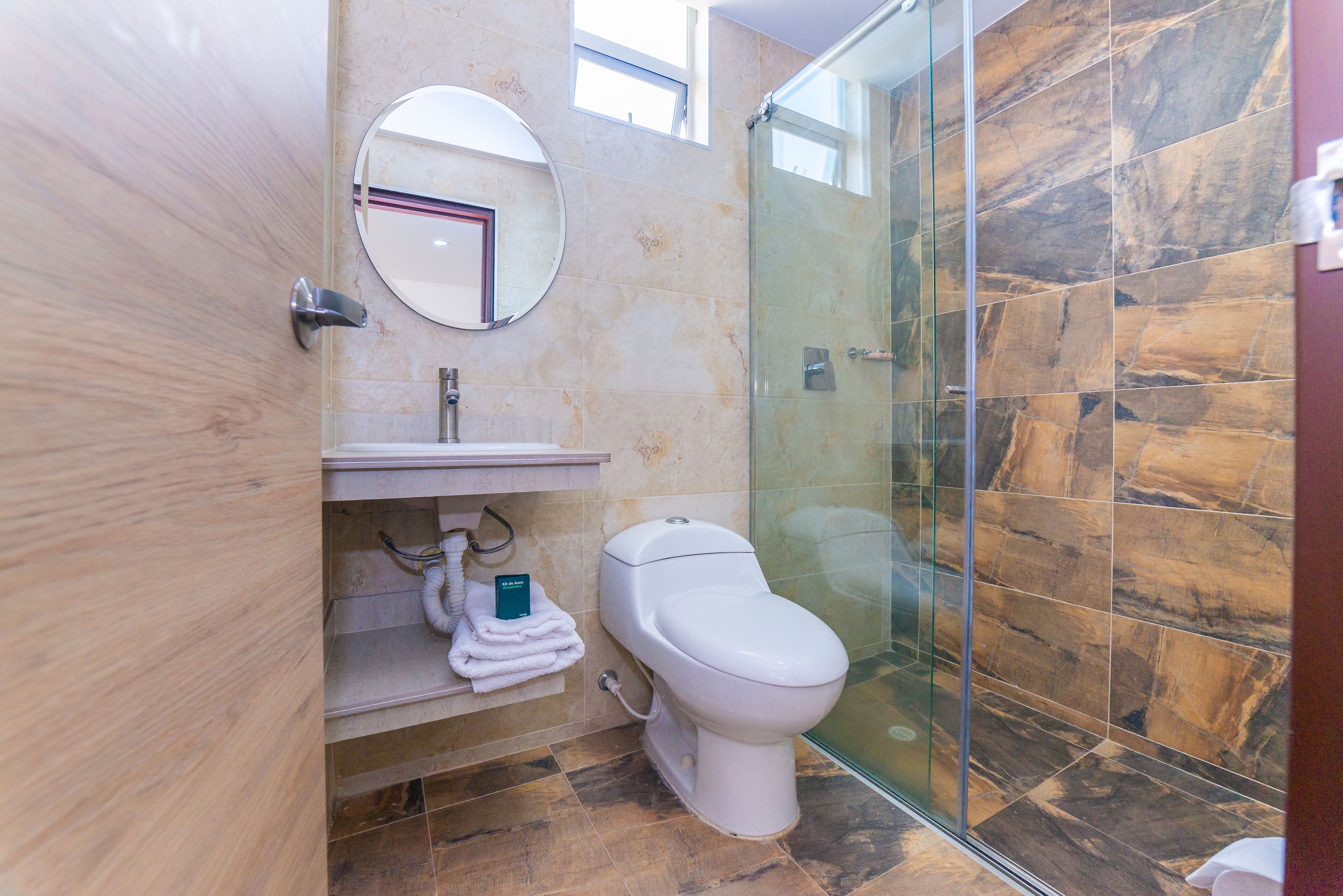 Un baño moderno con ducha de vidrio, inodoro y lavamanos con perchero.