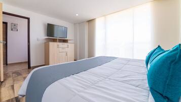 Habitación de hotel con una cama grande, televisor montado en la pared y un armario de madera.