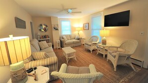 A living room with a sofa, armchairs, a coffee table, a TV, and a ceiling fan. - Beautiful home & short walk to beach, restaurants, and marinas in Rock Hall, MD (Rock Hall)