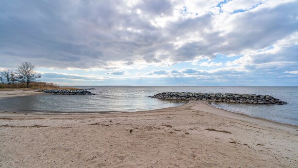 A beach with a rocky breakwater and a clear view of the sea. - Beautiful home & short walk to beach, restaurants, and marinas in Rock Hall, MD (Rock Hall)