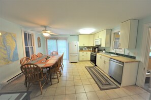 A compact kitchen with a dining area, featuring a refrigerator, microwave, stove, and sink.