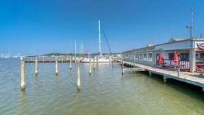 A waterfront dock with boats, a pier with red umbrellas, and a building with a flag. - Beautiful home & short walk to beach, restaurants, and marinas in Rock Hall, MD (Rock Hall)