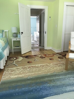 A bedroom with a bed, nightstand, and a view of the bathroom.