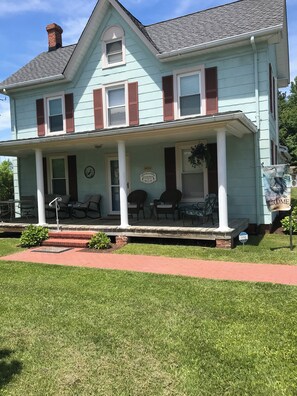A two-story house with a porch, a chimney, and a 'Welcome' sign.