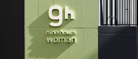 A building with a green facade and a sign that reads "9h nine hours woman".