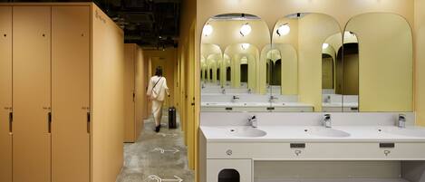 A modern bathroom with multiple sinks, mirrors, and lockers.
