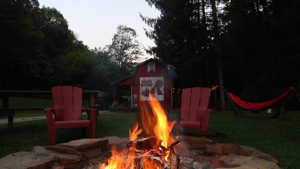 A campfire with red chairs and a hammock in a wooded area. - Cabin in Wayne National Forest with ride in/out access to Baileys Trail System (Millfield)