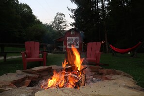 A campfire with red chairs and a hammock in a wooded area. - Cabin in Wayne National Forest with ride in/out access to Baileys Trail System (Millfield)