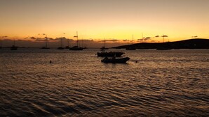 Un atardecer sobre un mar tranquilo con barcos.