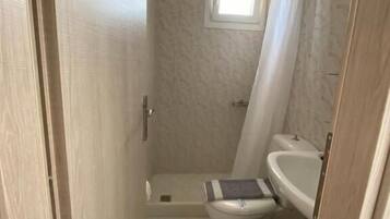 A compact bathroom with a shower, toilet, and sink.