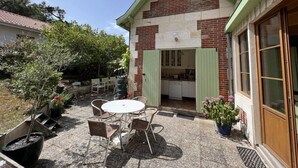 Une maison avec une façade en briques, une porte verte et un petit patio avec une table et des chaises.