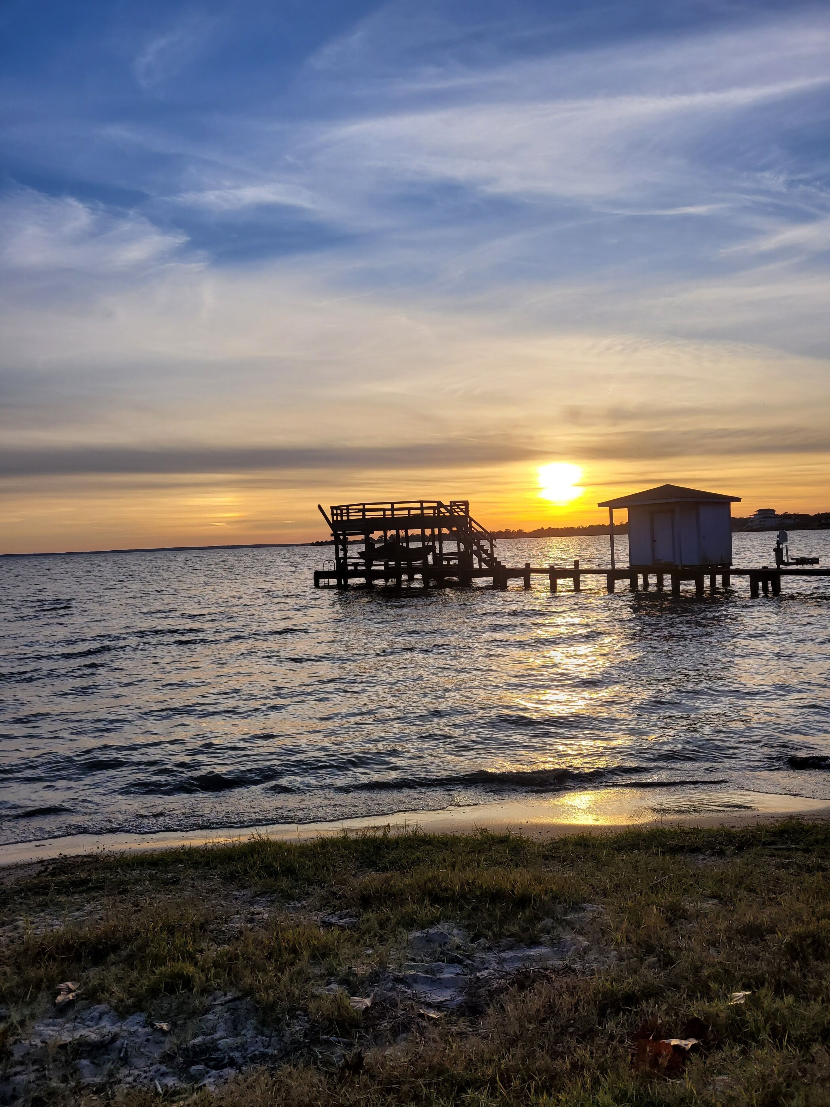 A sunset over a calm body of water with wooden structures and a small building on stilts.