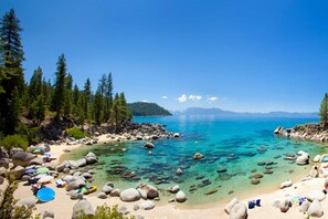 A beach with clear turquoise water, surrounded by rocks and trees. - Prestigious Location/Views/Near Casinos/Skiing (South Lake Tahoe)