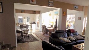 A spacious living area with a black leather sofa, a dining table, and a kitchen in the background. - Saint Palais sur Mer - BEAUTIFUL RENOVATED HOUSE – HEATED POOL – EVERYTHING ON FOOT (ST PALAIS SUR MER)
