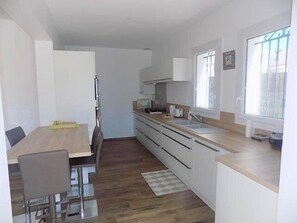 A compact kitchen with a dining area, wooden flooring, and a window with a view. - Saint Palais sur Mer - BEAUTIFUL RENOVATED HOUSE – HEATED POOL – EVERYTHING ON FOOT (ST PALAIS SUR MER)