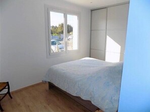 A bedroom with a bed, a window, and a view of parked cars outside. - Saint Palais sur Mer - BEAUTIFUL RENOVATED HOUSE – HEATED POOL – EVERYTHING ON FOOT (ST PALAIS SUR MER)