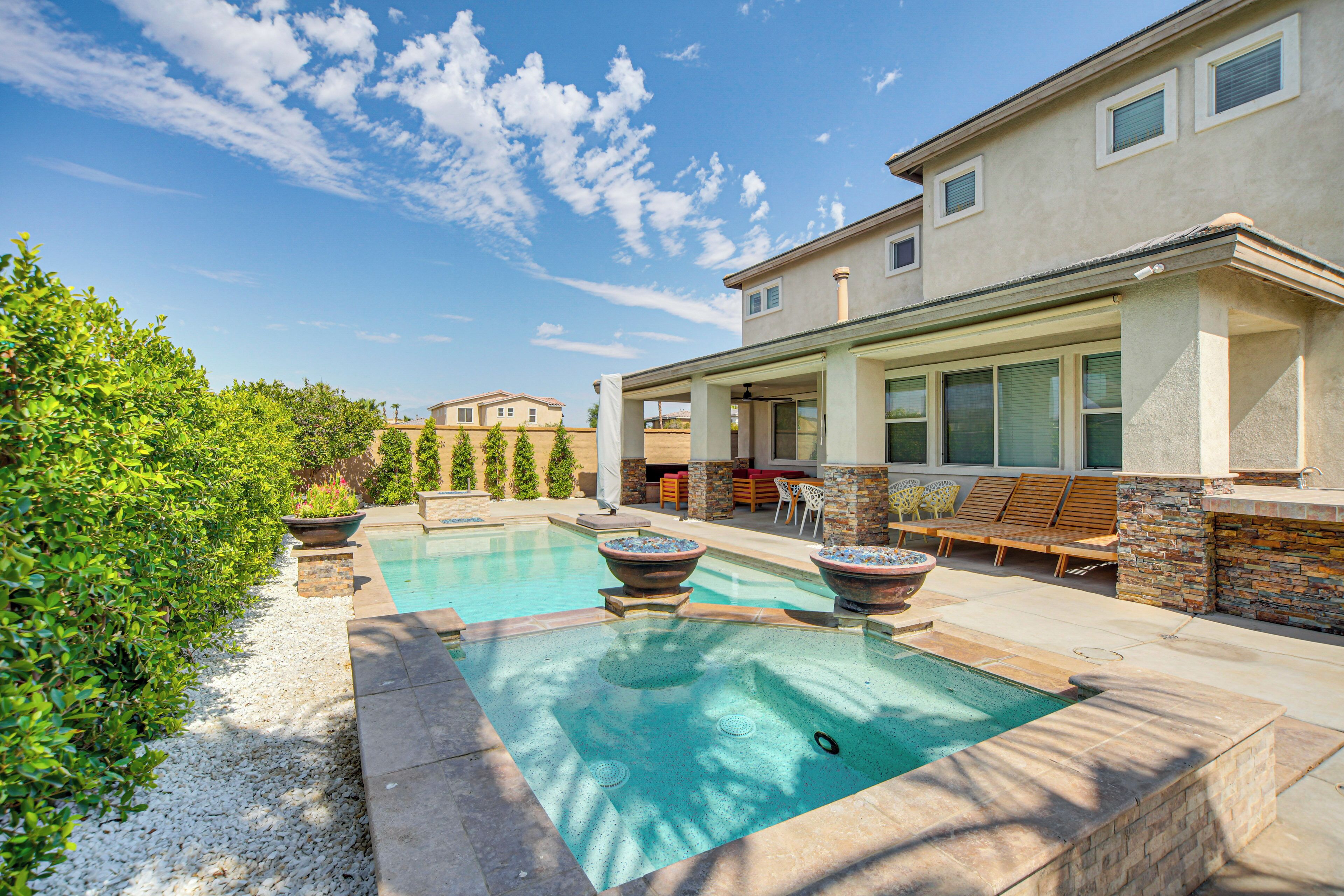 Ein modernes Haus mit Swimmingpool, Sitzgelegenheiten im Freien und einer Terrassenfläche.