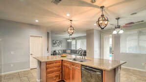 A spacious kitchen with granite countertops, wooden cabinets, and a dishwasher. - Spacious Indio Home: Pool, Grill, & Fire Pits (Indio)