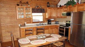 Eine Holzhütte mit Küche, Essbereich, Tisch, Stühlen, Kühlschrank und Mikrowelle.