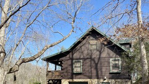 Eine rustikale Holzhütte mit Steinfundament, einer Holzterrasse und einer grünen Garagentür.