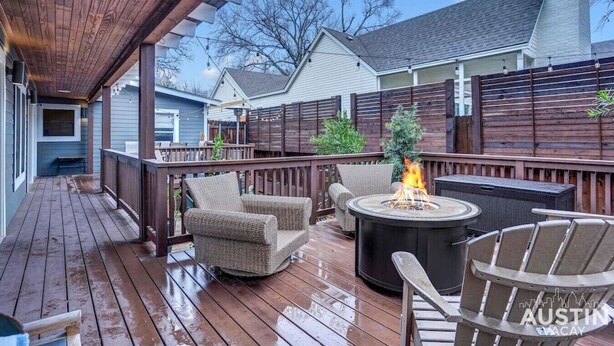 Une terrasse en bois avec des meubles d’extérieur, un foyer et un espace abrité.