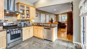Une cuisine spacieuse dotée de plans de travail en granit, d’une cuisinière en acier inoxydable, de meubles en bois et d’un grand îlot central avec un évier.