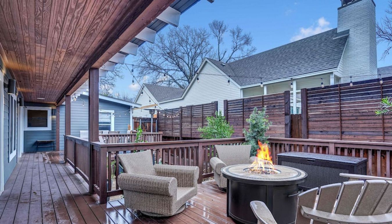 A wooden deck with outdoor furniture, a fire pit, and a covered area.