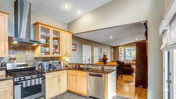 A spacious kitchen with granite countertops, a stainless steel stove, wooden cabinets, and a large island with a sink.