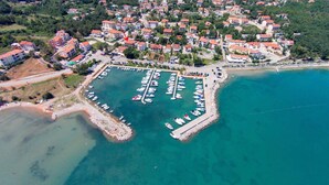 An aerial view of a coastal town with a marina, residential buildings, and a beach.
