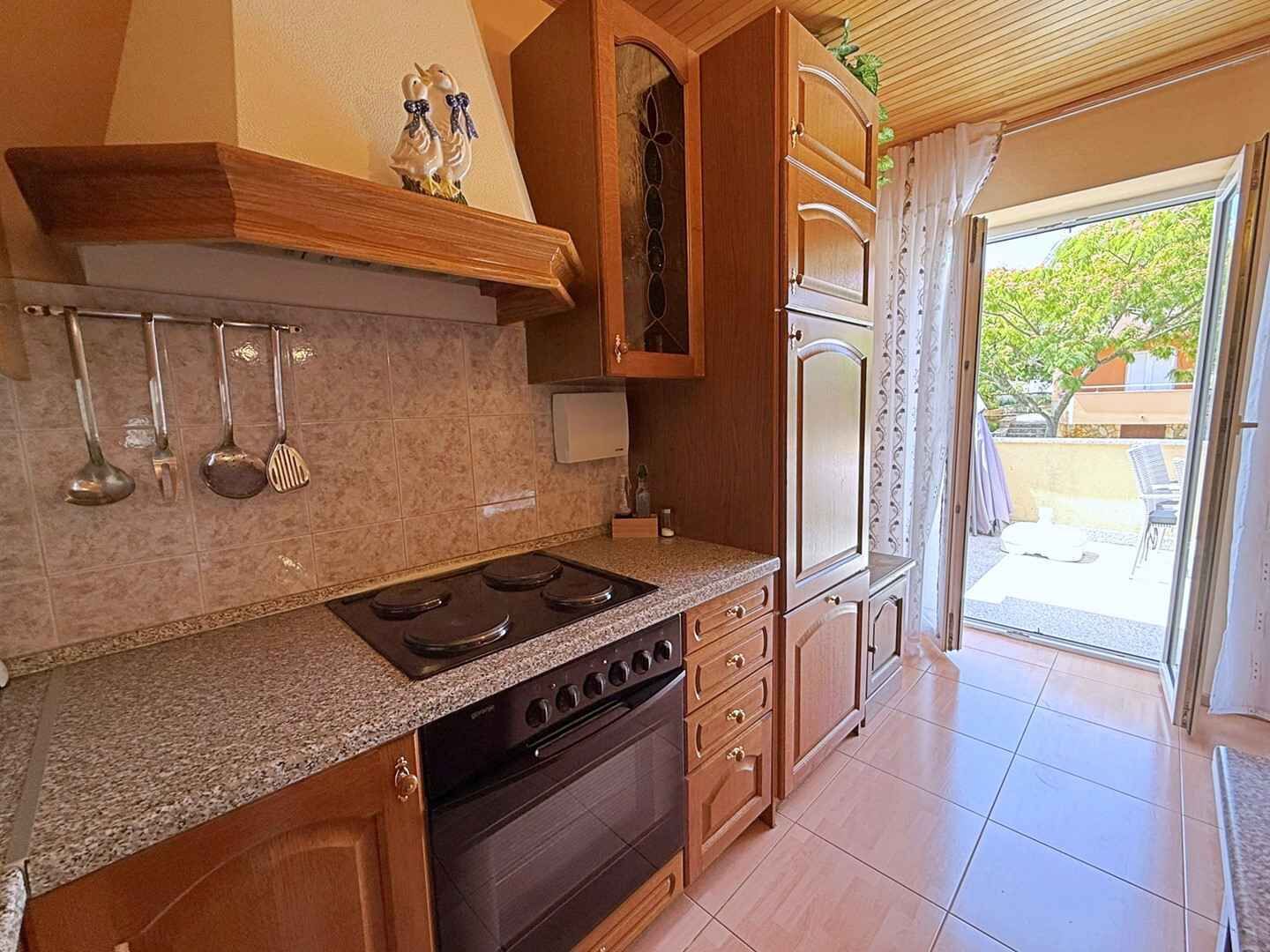 A kitchen with a stove, oven, and hanging utensils.