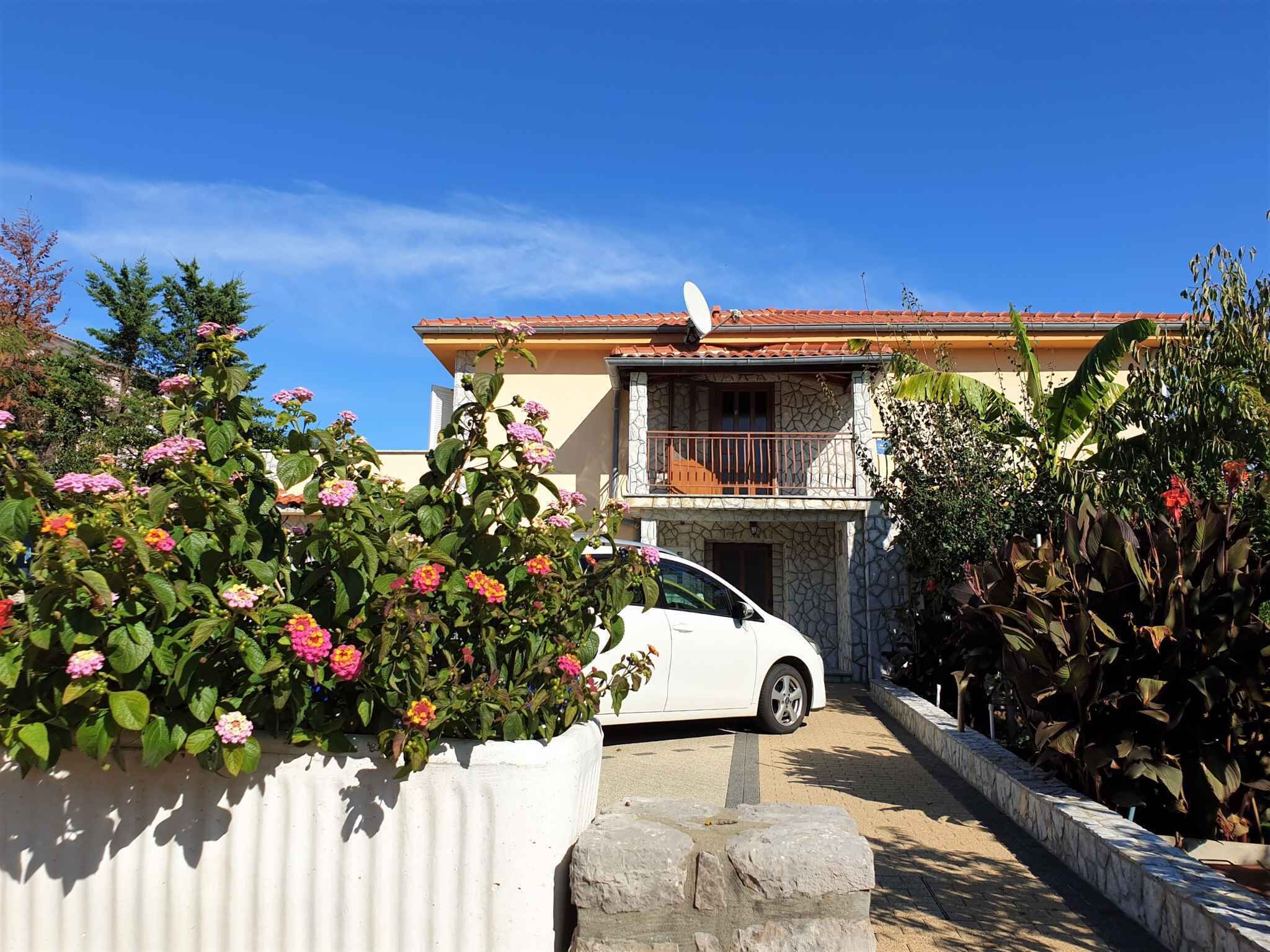 Une maison à deux étages avec une voiture blanche garée devant.