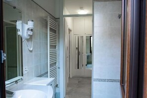 Une salle de bain équipée d’un lavabo, d’un miroir, d’un porte-serviettes et d’un espace douche.
