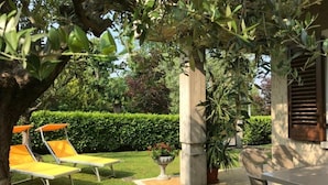 Ein Garten mit Tisch und Stühlen, einem kleinen Springbrunnen und einer Hecke im Hintergrund.