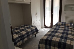 Une chambre avec deux lits, une armoire et un radiateur.