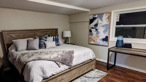 Un dormitorio con una cama de madera, una mesita de noche, una lámpara y una ventana.