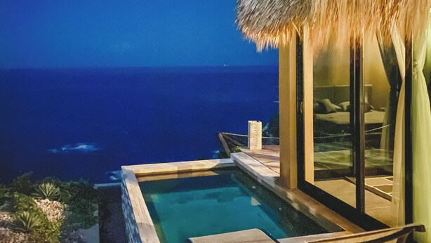 Ein Poolbereich mit Blick auf das Meer bei Nacht.