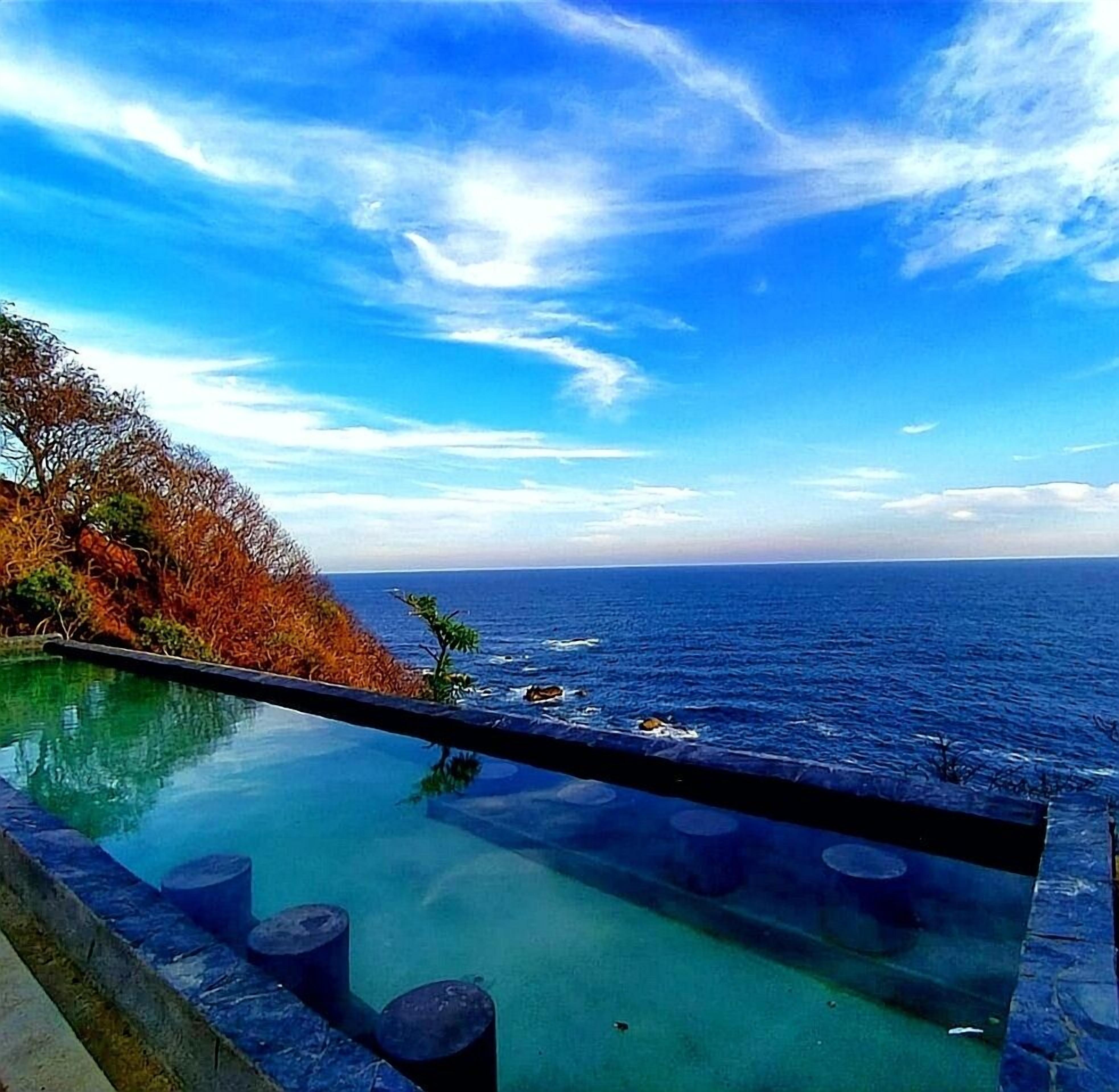 Una piscina al aire libre, sombrillas, sillones reclinables de piscina