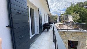 A modern outdoor patio with a black railing, a seating area with chairs, and a view of the backyard. - Villa and private pool - 5 min from the beaches and the city center - car rental (Bastia)