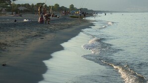 A beach with people fishing and swimming, a boat on the shore, and mountains in the background. - Villa and private pool - 5 min from the beaches and the city center - car rental (Bastia)