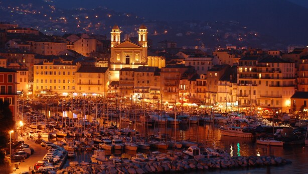 A marina with numerous boats docked, a prominent church with two towers, and surrounding buildings. - Villa and private pool - 5 min from the beaches and the city center - car rental (Bastia)