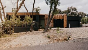 Ein modernes Haus mit Holzfassade, Auffahrt und einem kleinen Garten.