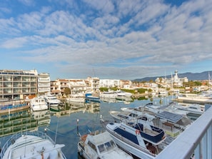 A marina with multiple boats docked, a lighthouse in the background, and buildings with balconies overlooking the water. - Nice apartment for 3 people with WIFI, TV and terrace (Empuriabrava)