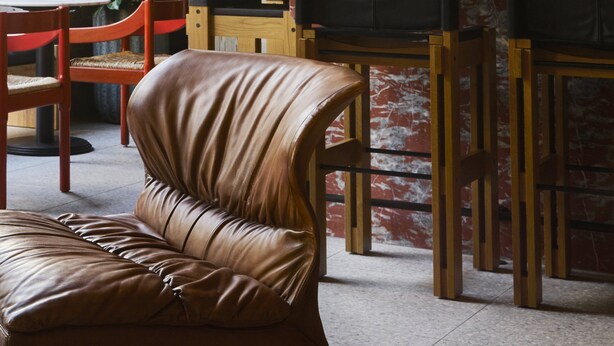A bar area with wooden chairs, a leather couch, and a brick wall. - Ace Hotel Sydney (Sydney)