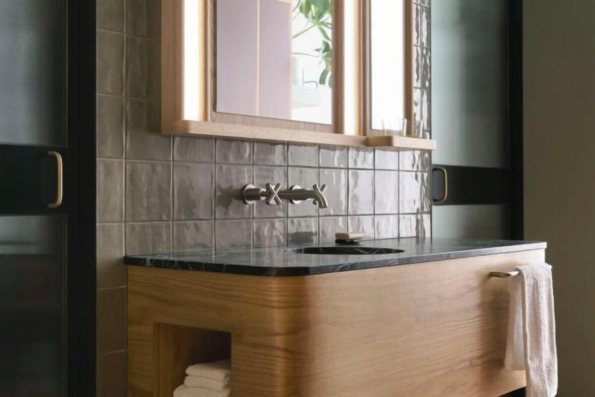 Un baño con tocador de madera, encimera negra y un mueble de pared con espejo.